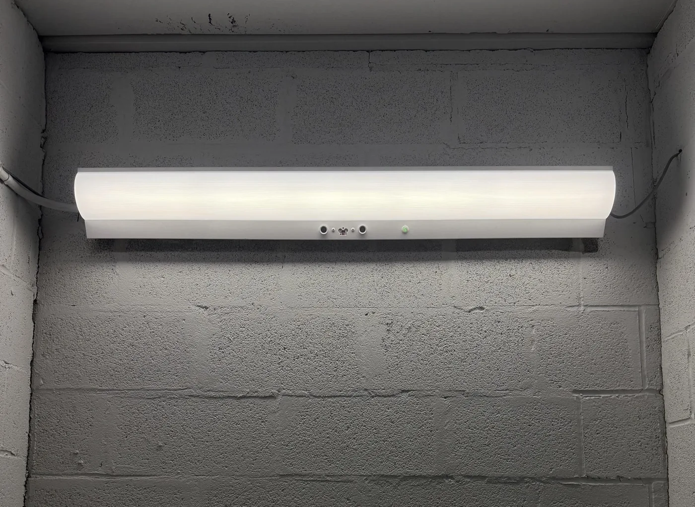 Wall-mounted light fixture installed on a block wall, photographed on an ESS job
